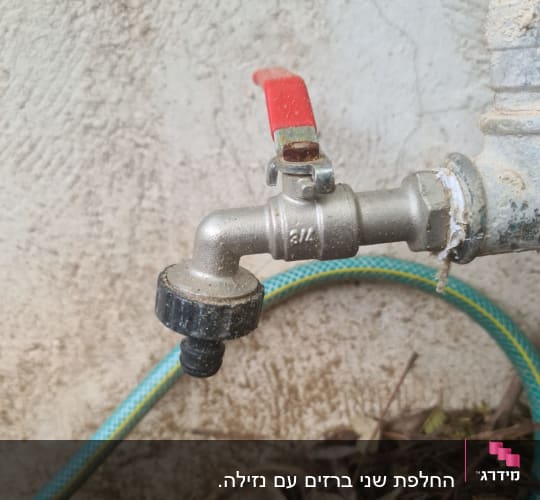 ברז מתכת עם ידית אדומה וצינור ירוק